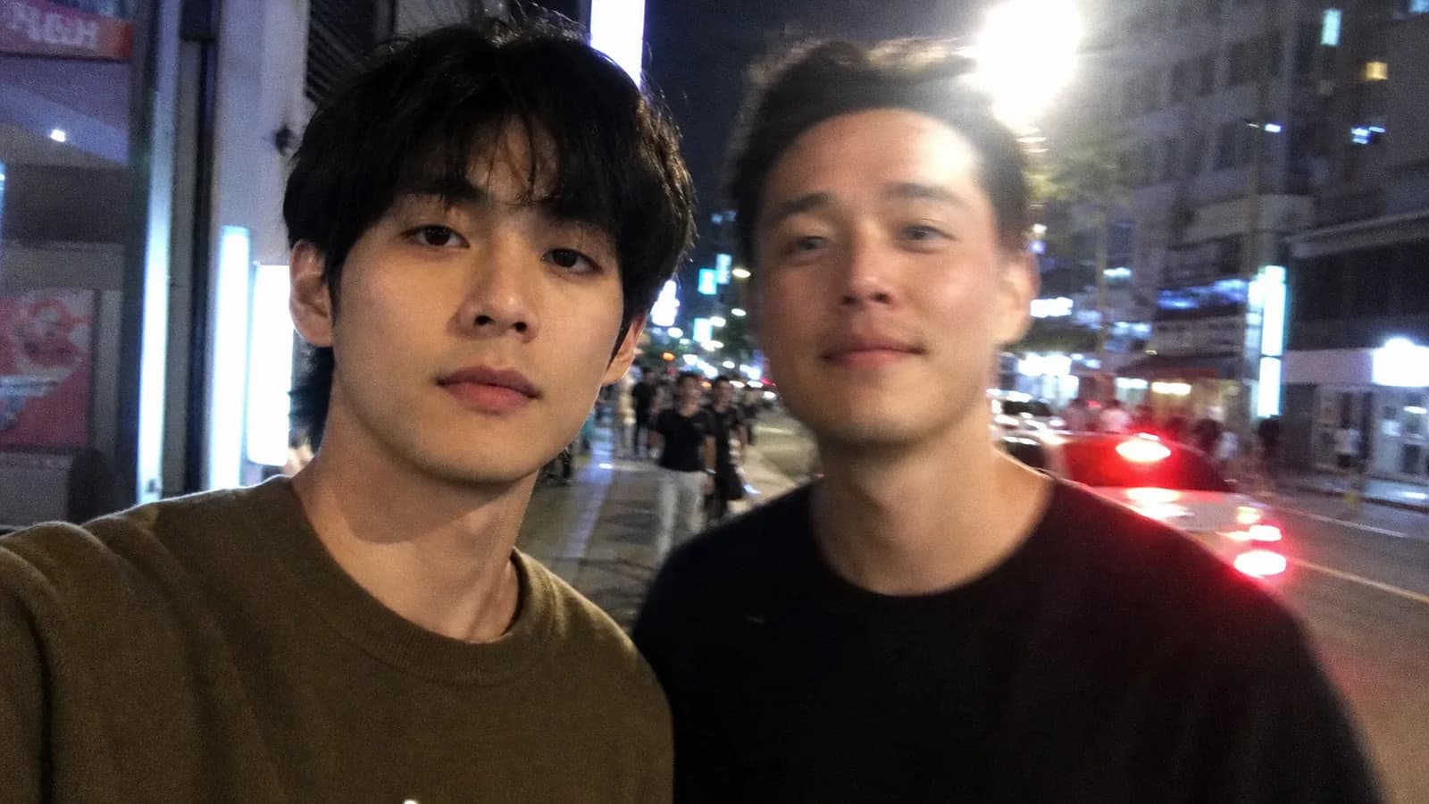 서울 밤거리에서 두 사람이 어색한 구도로 찍힌 듯한 흐릿한 아이폰 셀카 AI 결과물